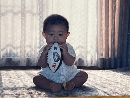 玩具のアメフトのボールで遊ぶ武田祐さん幼少期の画像